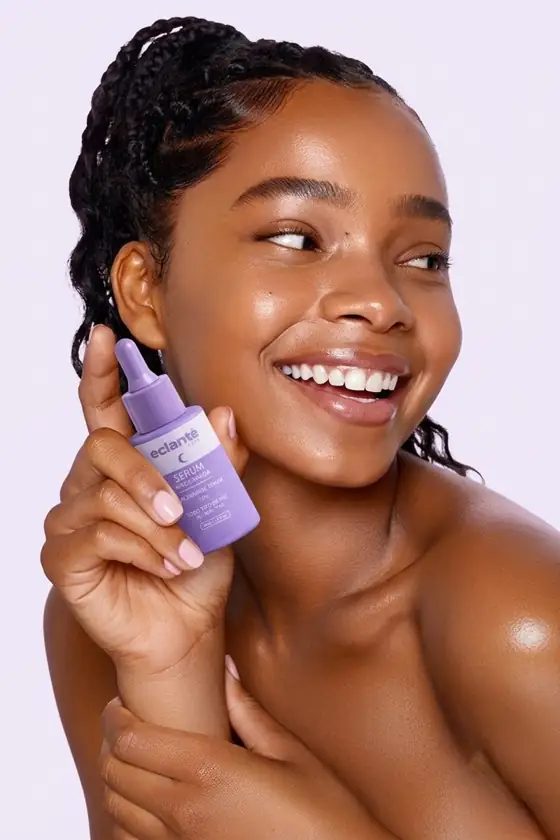 Modelo sonriendo sosteniendo el serum de niacinamida Eclante junto a su rostro